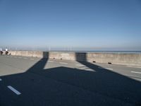 the shadow of an airplane is cast on the road by the ocean as it passes over the bridge