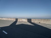 the shadow of an airplane is cast on the road by the ocean as it passes over the bridge