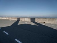 the shadow of an airplane is cast on the road by the ocean as it passes over the bridge