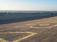 a street with a yellow line painted on it in the sand with an ocean in the background