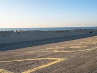 a street with a yellow line painted on it in the sand with an ocean in the background