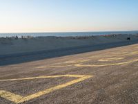 a street with a yellow line painted on it in the sand with an ocean in the background