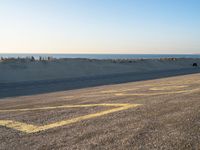 a street with a yellow line painted on it in the sand with an ocean in the background