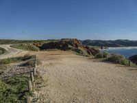 a large long sandy hill with a road going to the ocean underneath a clear blue sky