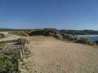 a large long sandy hill with a road going to the ocean underneath a clear blue sky