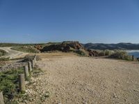 a large long sandy hill with a road going to the ocean underneath a clear blue sky