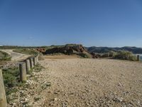 a large long sandy hill with a road going to the ocean underneath a clear blue sky