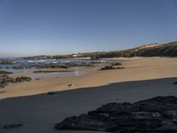 a beach area with a rocky shoreline and an ocean shoreline in the background and a beach on top of it