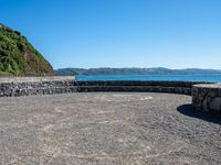 a view of the ocean from a sandy beach with a rock wall on it's edge