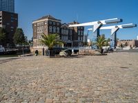 an empty bricked courtyard area by the water with water feature and buildings in the back ground