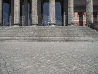 there is a man with an umbrella walking up some steps in front of a large building