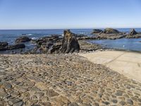 a sidewalk with stepping steps leading to the water on a rocky shore with clear blue sky in background