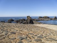 a sidewalk with stepping steps leading to the water on a rocky shore with clear blue sky in background