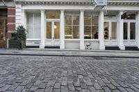 a paved cobblestone street and brick buildings in the city with people walking on the sidewalk