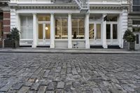 a paved cobblestone street and brick buildings in the city with people walking on the sidewalk