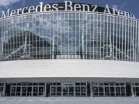 the entrance to the mercedes benz arena is visible behind glass walls and stone floors,