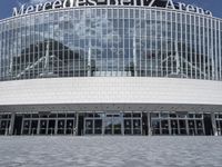 the entrance to the mercedes benz arena is visible behind glass walls and stone floors,