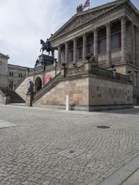 a building has people walking down the steps to it with sculptures on each side of it