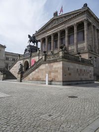 a building has people walking down the steps to it with sculptures on each side of it