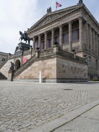 a building has people walking down the steps to it with sculptures on each side of it