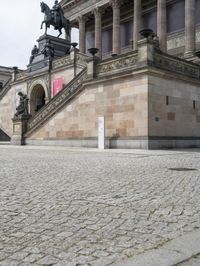 a building has people walking down the steps to it with sculptures on each side of it