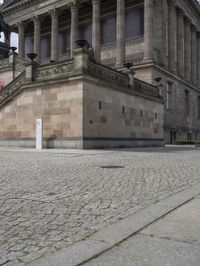 a building has people walking down the steps to it with sculptures on each side of it