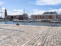 a cobblestone road in an outdoor setting with boats docked at the water's edge