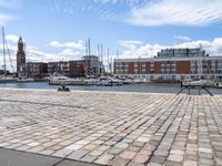 a cobblestone road in an outdoor setting with boats docked at the water's edge