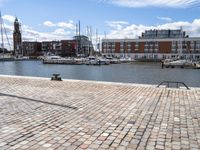 a cobblestone road in an outdoor setting with boats docked at the water's edge