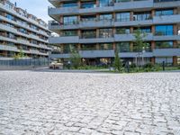 an empty cobblestone road near a parking garage and office buildings in a modern urban area