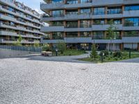 an empty cobblestone road near a parking garage and office buildings in a modern urban area