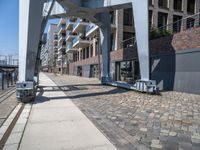 a paved walkway under a large metal structure, with a street light next to it