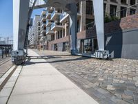 a paved walkway under a large metal structure, with a street light next to it