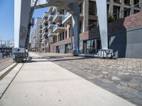 a paved walkway under a large metal structure, with a street light next to it