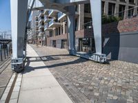 a paved walkway under a large metal structure, with a street light next to it