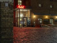 a small building with an illuminated neon sign and benches outside the door and windows on both sides