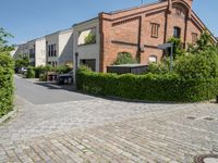 a brick paved parking lot with cars and buildings in the background and trees surrounding it