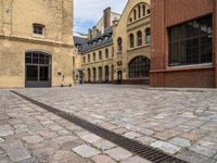 a cobble stone street with buildings on each side of it and one building has windows