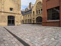 a cobble stone street with buildings on each side of it and one building has windows