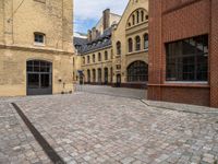 a cobble stone street with buildings on each side of it and one building has windows