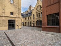 a cobble stone street with buildings on each side of it and one building has windows