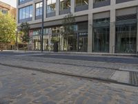 a cobble stone street with buildings and a trolley on one side and a bus parked on the other