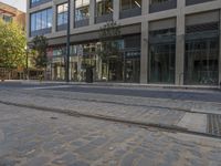 a cobble stone street with buildings and a trolley on one side and a bus parked on the other