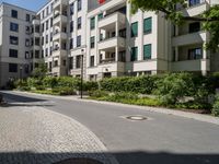 a stone sidewalk in front of an apartment building in germany, as well as landscaping