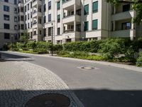 a stone sidewalk in front of an apartment building in germany, as well as landscaping