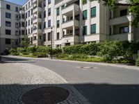 a stone sidewalk in front of an apartment building in germany, as well as landscaping