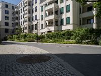 a stone sidewalk in front of an apartment building in germany, as well as landscaping