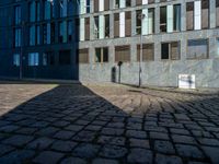 a shadow on a street next to a building with windows and a sign in the corner