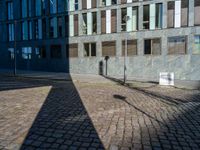 a shadow on a street next to a building with windows and a sign in the corner