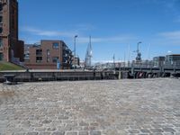 a brick walkway that leads to a boat dock in a harbor with buildings next to it